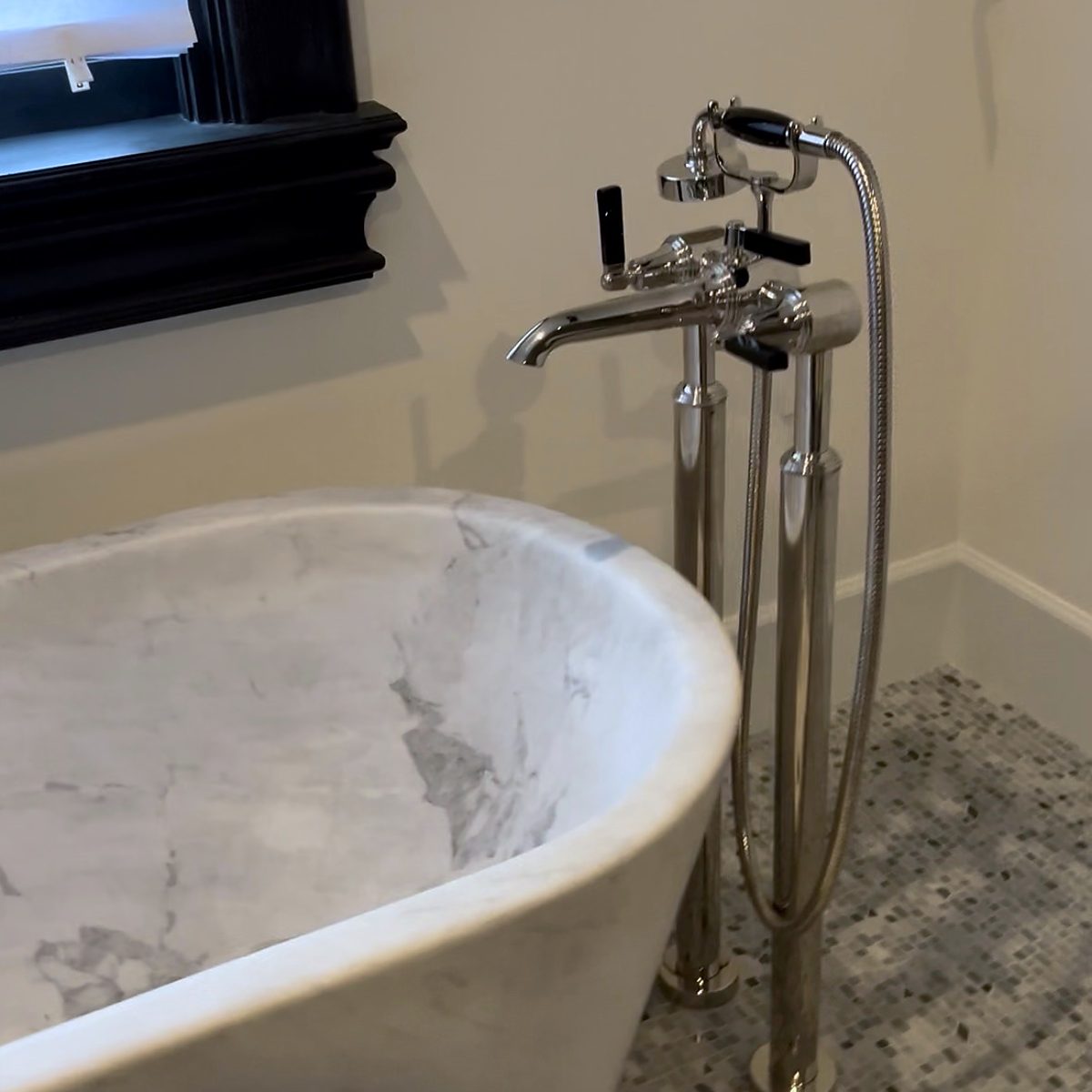 Freestanding tub filler with hand shower installed beside a soaking tub